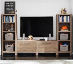 an entertainment center with bookshelves, baskets and a television