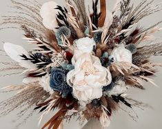 an arrangement of flowers and feathers in a vase