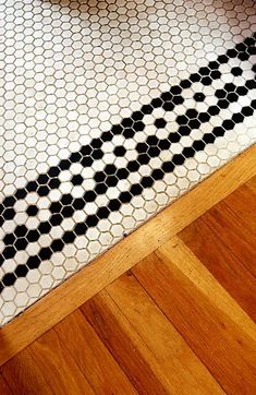 a bathroom with black and white tiles on the floor next to a wood flooring