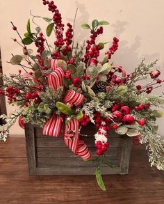 a christmas arrangement in a wooden box with red berries and greenery