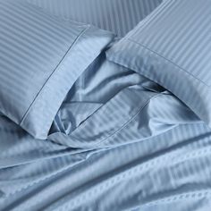 an unmade bed with blue sheets and pillowcases on top of each other