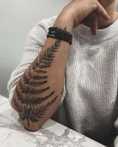 a person sitting at a table with a tattoo on their arm