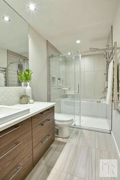 a large bathroom with a walk in shower next to a white toilet and wooden cabinets