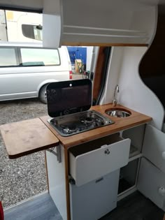 an oven and sink in the back of a camper with a van behind it