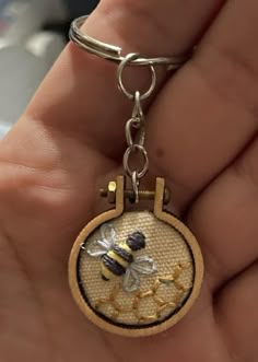 a person holding a key chain with a bee on it