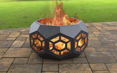 a fire pit sitting on top of a brick patio next to a green grass field