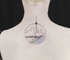 the back of a woman's neck with a city skyline tattoo on it