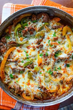 a casserole with sausage, peppers and cheese in a pan on a towel