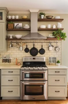 a stove top oven sitting inside of a kitchen next to wooden shelves filled with pots and pans