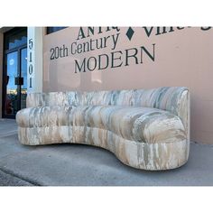 a curved couch sitting in front of a building