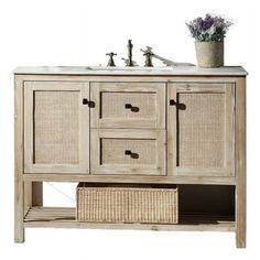 a white sink sitting under a wooden cabinet next to a vase with flowers in it