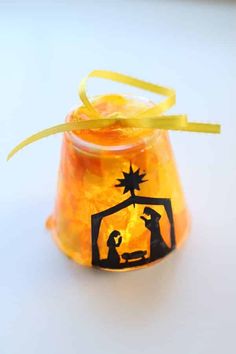 a small glass jar filled with candy and a nativity scene on it's lid