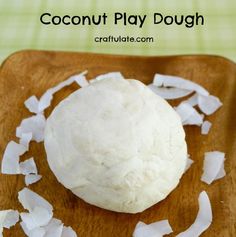 coconut play dough on a wooden cutting board with shredded white paper around it and text overlay that reads, coconut play dough