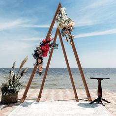 a wedding arch with flowers on the beach