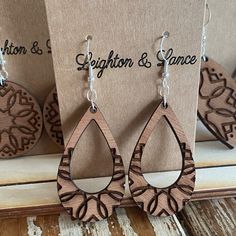 three wooden earrings are on display in front of a card and some other wood pieces