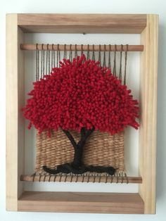 a red tree is placed in a wooden frame on the wall above a woven basket