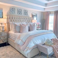 a bedroom with white and pink bedding, chandelier, chair, mirror and two nightstands