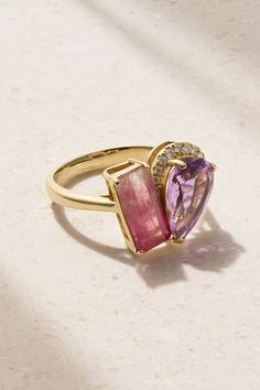 a pink and yellow ring with two hearts on it's sides, sitting on a white surface