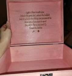 a pink box with writing on it and a person's hand holding the lid