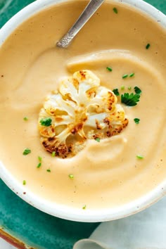 a white bowl filled with soup and topped with cauliflower