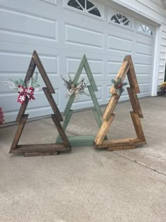 three wooden christmas trees sitting in front of a garage