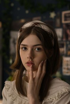 a young woman with her hand on her chin looking at the camera while wearing a headband