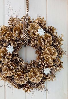 a christmas wreath hanging on a door with pine cones and snowflakes around it