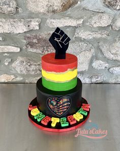 a multi - colored cake with a black fist on top