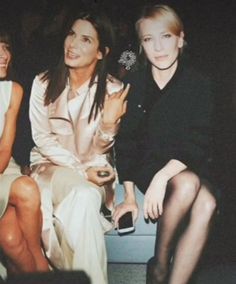 three women sitting next to each other at a fashion show