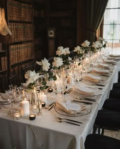 a long table is set up with white flowers and candles for an elegant wedding reception