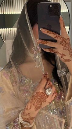 a woman with henna on her hand taking a selfie in front of a mirror