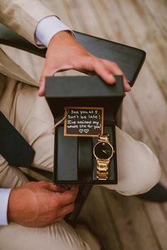 a man is holding a watch in his lapel and wearing a gold bracelet with writing on it