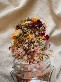 a jar filled with dried flowers on top of a white cloth