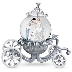 a snow globe with a bride and groom in it on top of a silver carriage