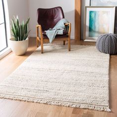 a living room area with a chair, rug and potted plant