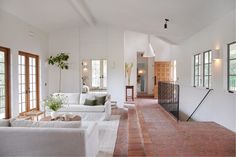 a living room filled with white furniture and lots of windows on top of it's walls