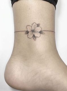 a woman's ankle with a flower tattoo on the side of her foot,