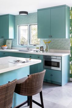 a kitchen with blue cabinets and wicker chairs in front of the countertop area