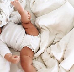 a baby laying in bed with white sheets