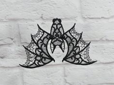 a black lace mask hanging on a brick wall in front of a white brick wall