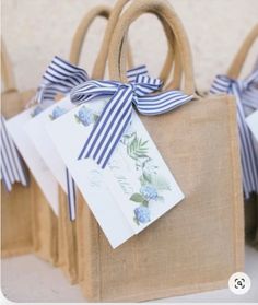 three bags with blue and white ribbons tied to them, one has a tag on it