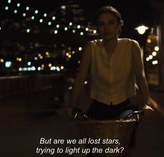 a woman riding a bike down a street at night with the caption, but are we all lost stars trying to light up the dark?