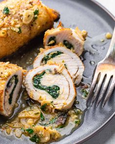 two slices of chicken with spinach and cheese on a plate next to a fork