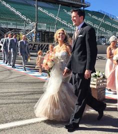 the bride and groom are walking down the aisle at the football stadium after their wedding ceremony