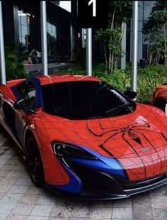 a red and blue sports car parked in front of a building with the words spiderman on it