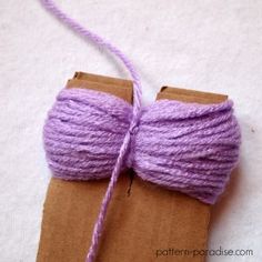 a purple ball of yarn tied to a piece of brown paper