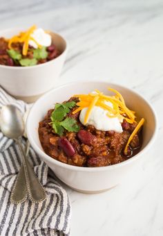 two bowls filled with chili and sour cream