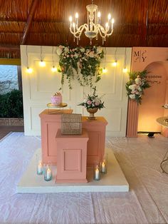 a small pink church with candles and flowers on the alter, in front of a chandelier