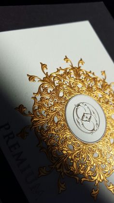 an ornate gold and white business card with the letter g on it's side