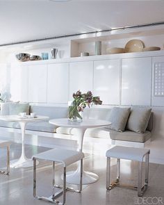 a room with white furniture and flowers in vases on the table, along with two benches